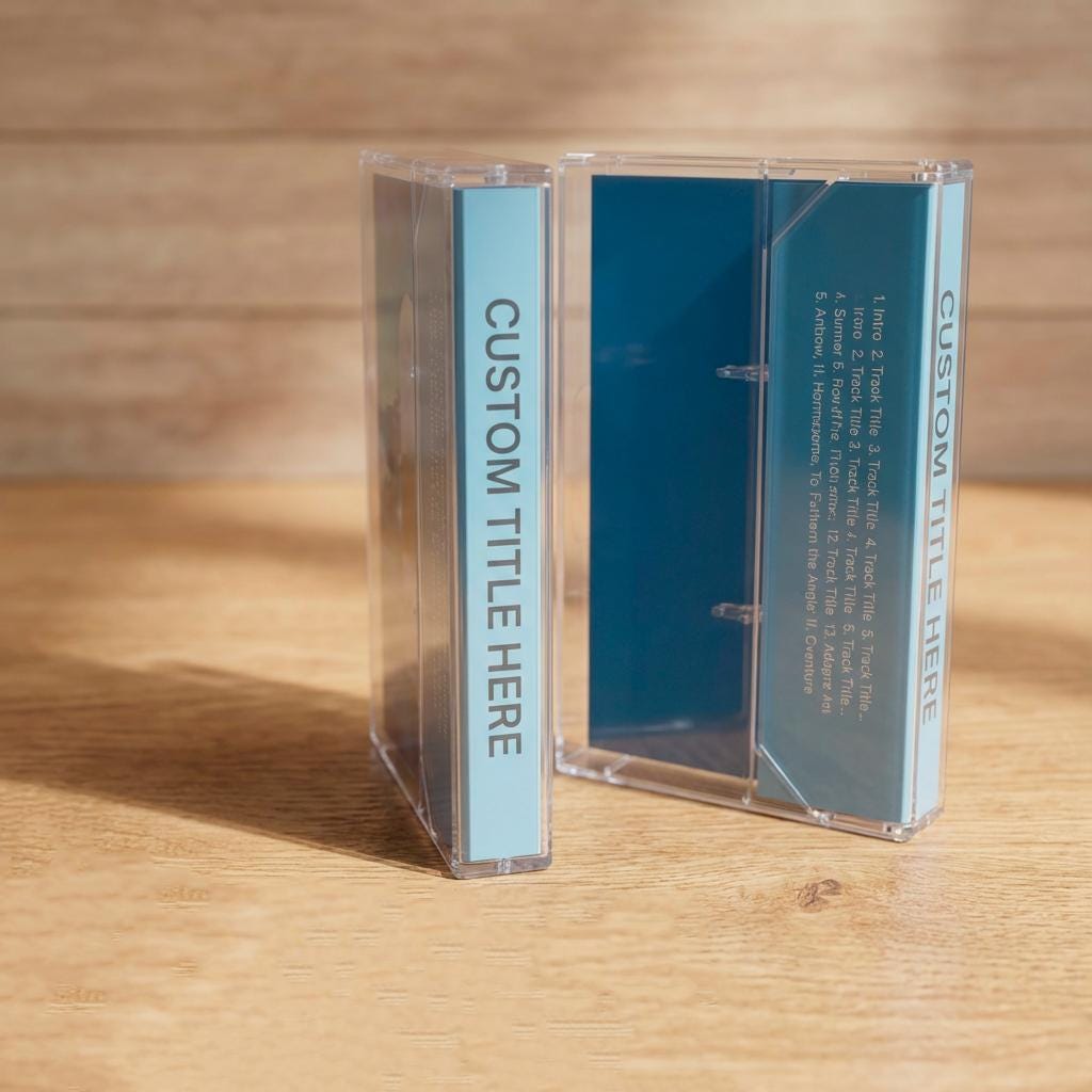 Two transparent cassette cases are placed on a wooden surface, with the text "CUSTOM TITLE HERE" visible on the cases.