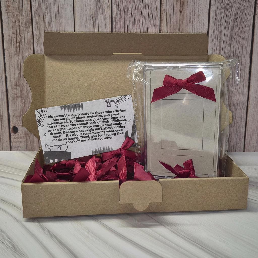 a cardboard box containing a card and a small object, both with red ribbons. The card appears to be a tribute or message, while the small object is not clear enough to identify its purpose. The box is placed on a wooden surface, and the background is a wooden wall.